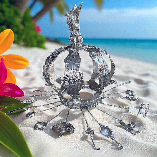 Decorative silver crown on a sandy beach with flowers and ocean in the background