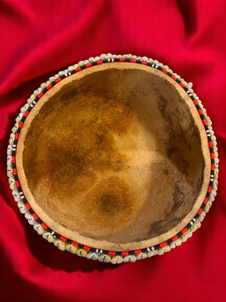 Beaded gourd half on a red fabric background