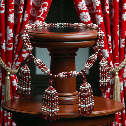 Decorative red and white tassels on a wooden pedestal with red floral curtains in the background.