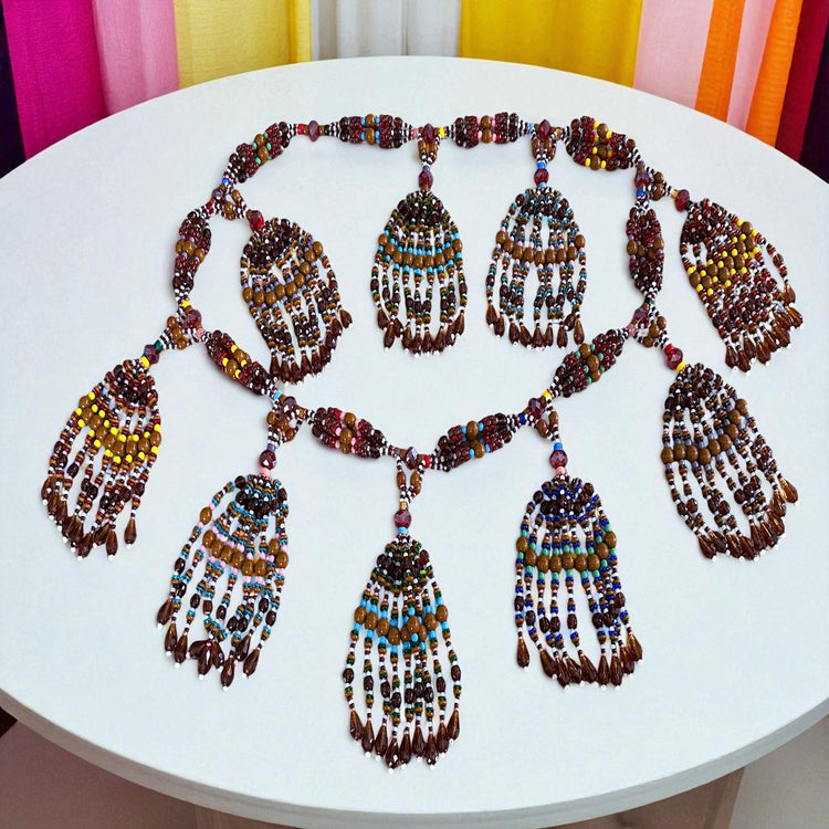 Colorful beaded necklace on a white table with colorful curtains in the background