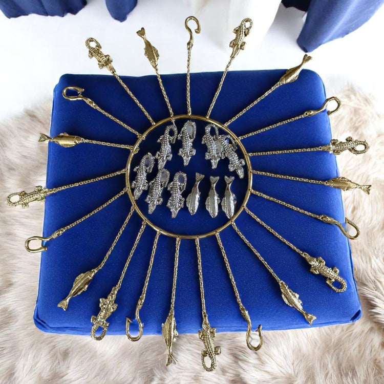 Olosa tools with gold and silver fish on a blue cushion against a white background
