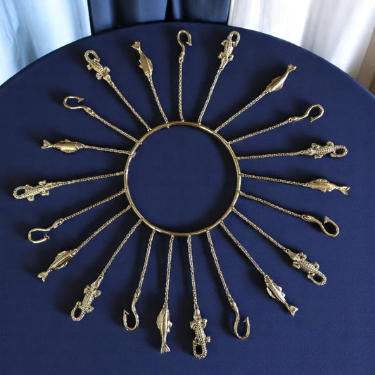A handcrafted set of metal tools with a radiant brass-tone finish, hanging from a circular hoop, designed to represent the Orisha Olósa.