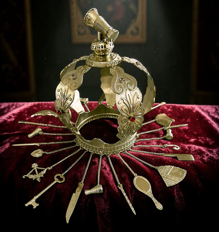 Decorative gold colored crown with hanging adornments on a red velvet surface