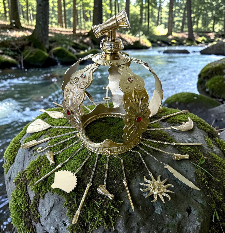 Decorative metal crown on a mossy rock with a forest stream in the background