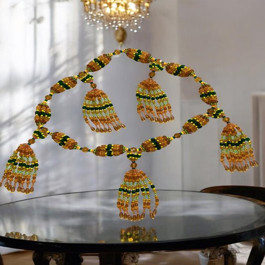 A detailed image of a Yoruba mazo, a traditional West African beaded necklace, displayed on a reflective surface, featuring intricate designs with green, yellow, and topaz colored beads.