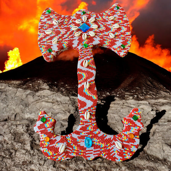 Colorful beaded double headed axe with shells and stones against a  volcanic background