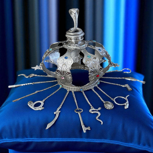 Decorative silver crown with tools on a blue cushion against a blue curtain background