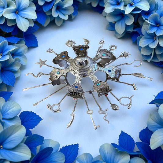 Decorative silver crown with gemstones surrounded by blue flowers