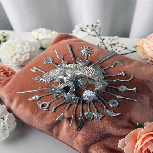 top view of silver colored decorative crown on a coral colored fabric pillow and background with flowers around