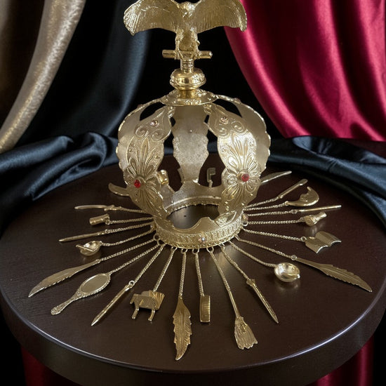 Decorative gold crown with vulture topping on a dark surface