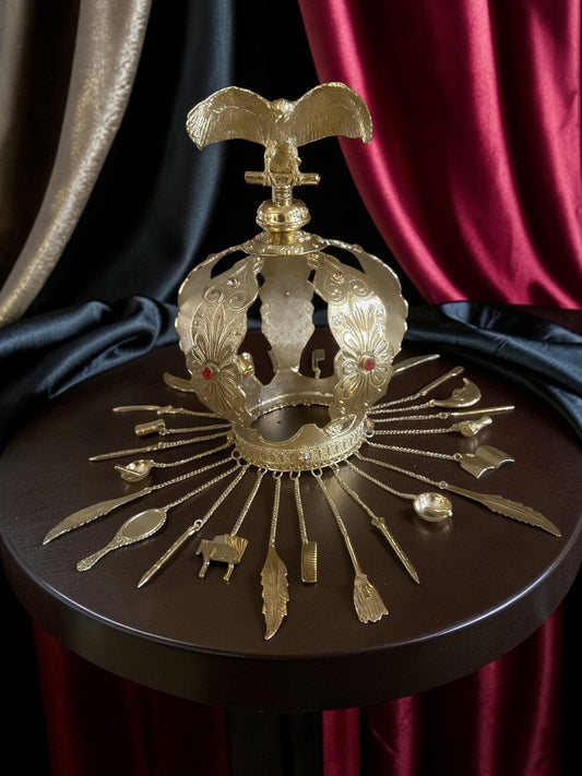 Decorative gold crown with vulture topping on a dark surface