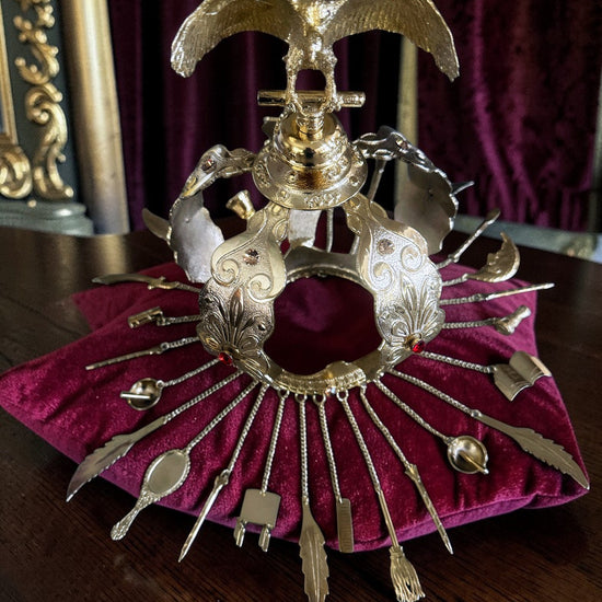 Decorative gold colored crown with red and amber colored stones on a burgandy cushion