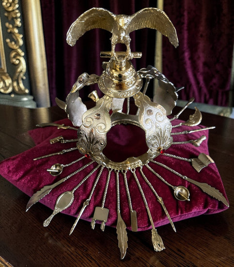 Decorative gold colored crown with red and amber colored stones on a burgandy cushion