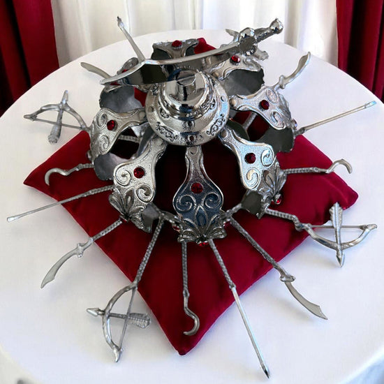 Decorative metal crown piece on a red cloth with a white curtain background