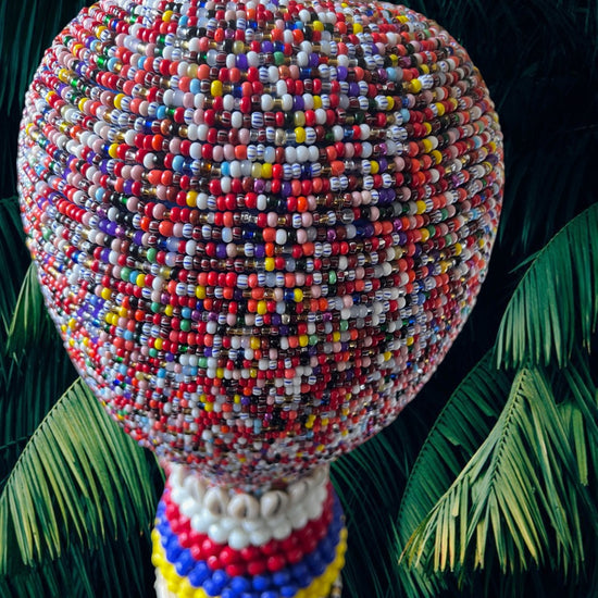 Colorful beaded gourd against a tropical leaf background
