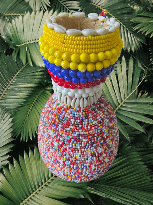 Colorful beaded gourd with cowrie shells on green leaves