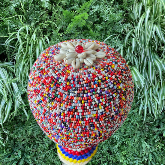 Multicolored beaded gourd against green foliage background
