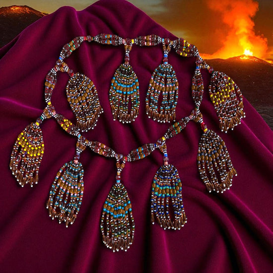 Decorative necklace with multicolored beads on a red fabric with a mountain and sunset background