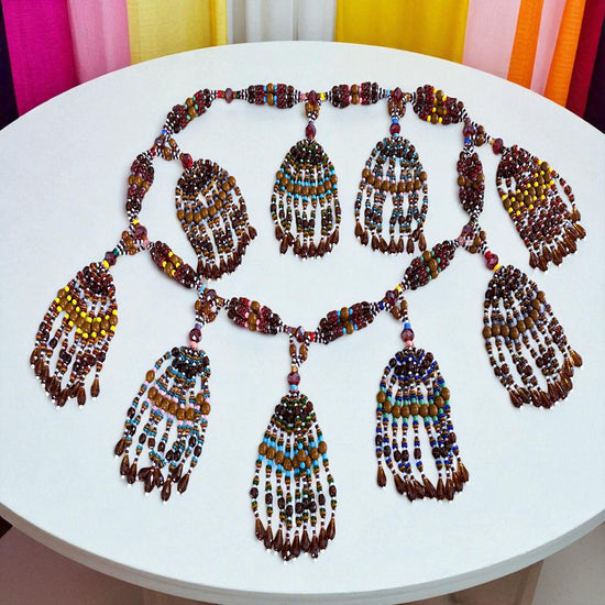 Colorful beaded necklace on a white table with colorful curtains in the background