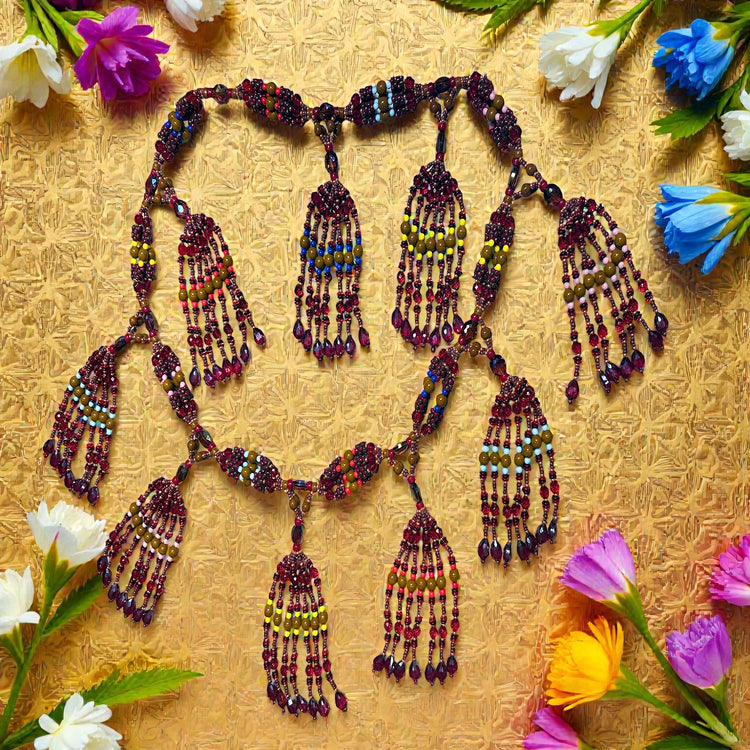 Beaded necklace with colorful tassels on a textured yellow background with flowers.