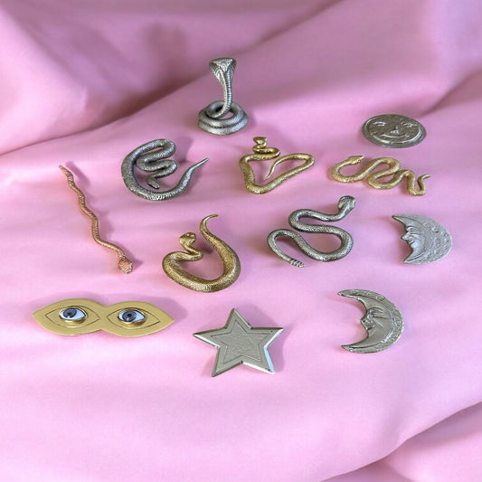 Collection of metallic tools for Nana Buruku on a pink fabric background