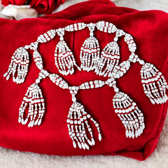 A petite 4-string mazo necklace for Obatala (Ayaguna) with red, white, and frosted Czech glass beads, displayed on a red fabric surface.