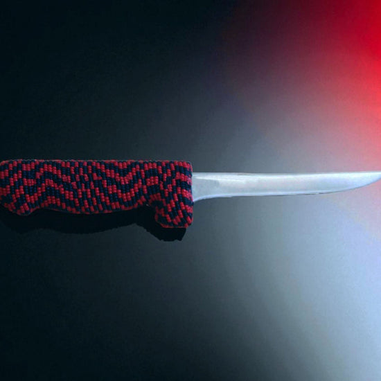 Knife with a red and black patterned handle on a dark background