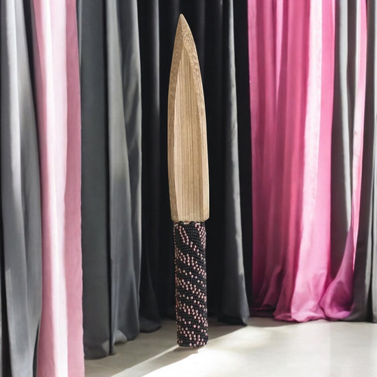 Decorative knife with a beaded handle against a colorful curtain background