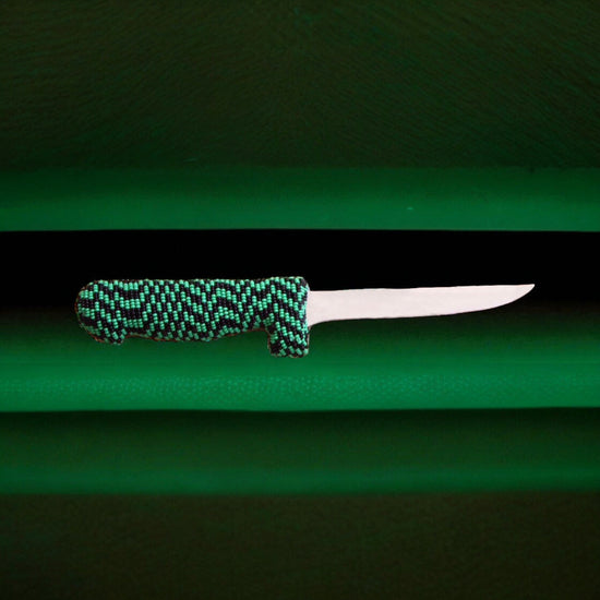 Knife with a green and black patterned handle on a green background