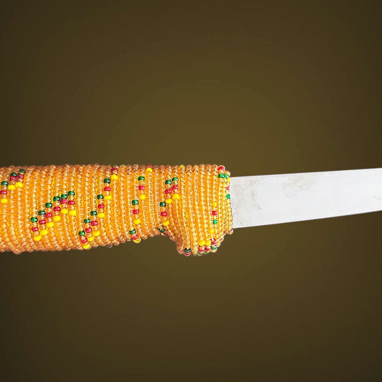 Knife with a decorative yellow beaded handle on a dark background