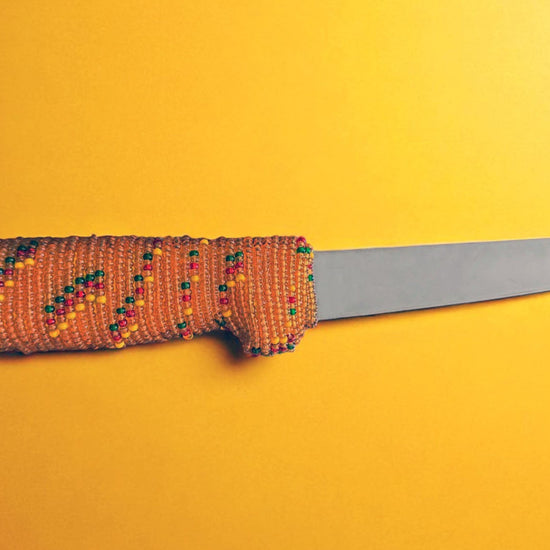 Knife with a beaded handle on a yellow background