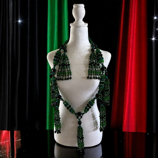 A mannequin displaying a petite mazo (necklace) with green beads, designed in honor of Oggun, featuring multiple tiers and tassel details.