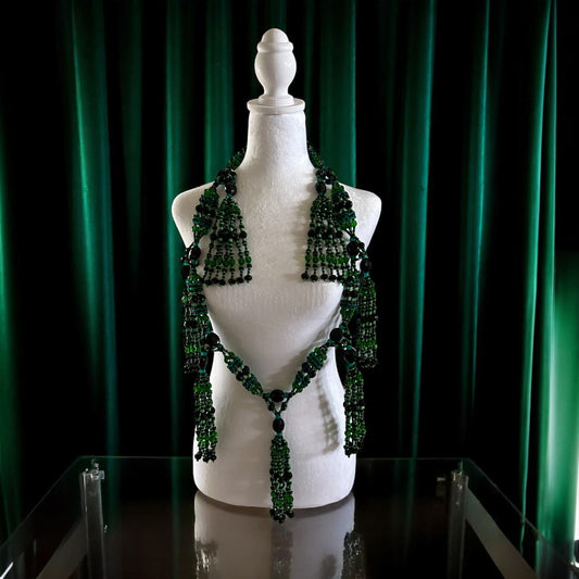 Mannequin with green and black  beaded necklace against a green curtain background