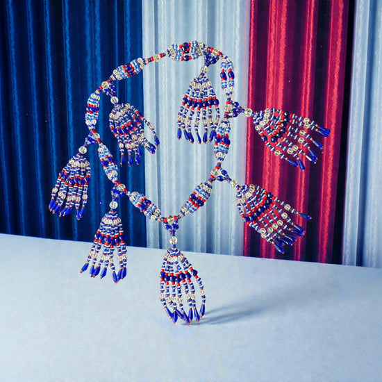 Decorative Necklace with blue, red, and silver tassels against a colorful curtain background