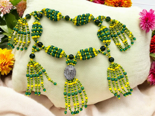 A beaded necklace with green and yellow strings arranged in a pattern, featuring a medallion with an elephant design.