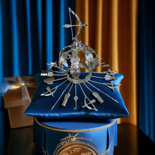 Decorative silver crown on a blue cushion with a gold base against a blue curtain background