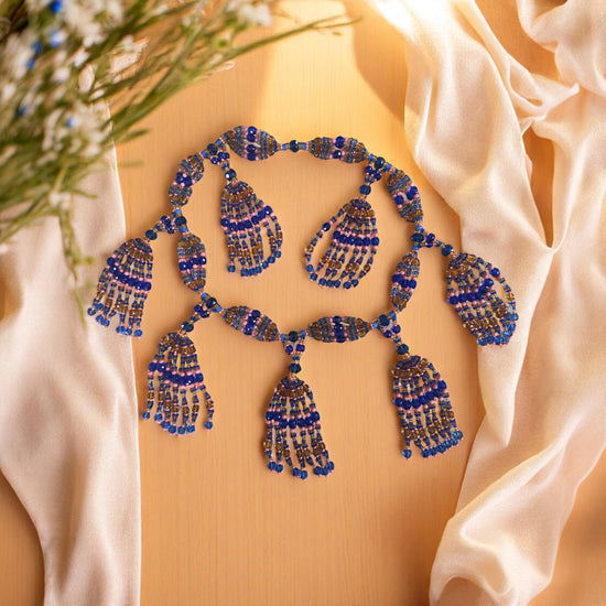 Blue beaded necklace on a beige fabric background.