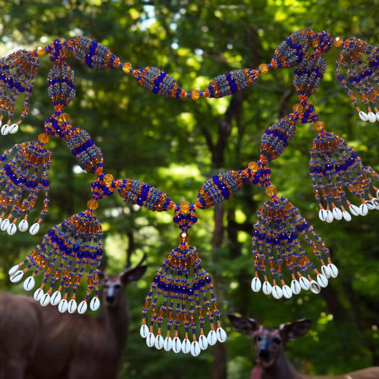 A colorful beaded mazo with multiple strands featuring sapphire blue, topaz, and pink coral acrylic beads, with a natural background.