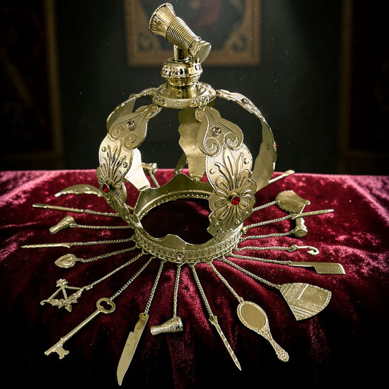 Decorative gold colored crown  with hanging adornments on a red velvet surface
