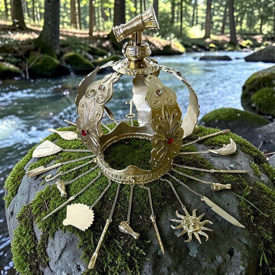Decorative metal crown on a mossy rock with a forest stream in the background