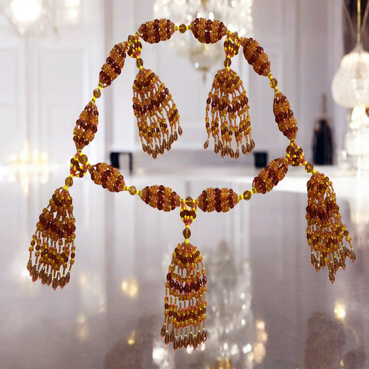 A detailed image of a 10-string mazo featuring topaz, yellow, and pink coral beads, arranged in a spiritual or ceremonial necklace style.