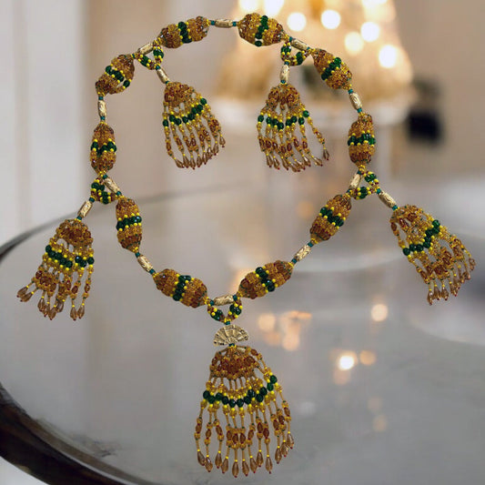 A detailed image of a 10-string glass mazo necklace designed for Oshun, featuring vibrant topaz and green beads with yellow accents, and a hand fan accessory.