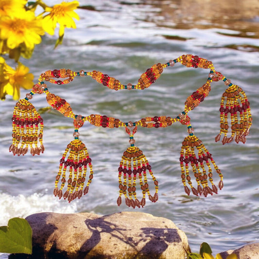 A colorful beaded necklace with multiple drop-shaped pendants, displayed against a water and rock background.
