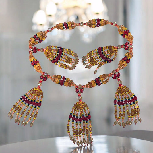 A detailed image of a petite mazo necklace designed for Oshun (Ikole), featuring topaz and red colored beads with black accents, displayed against a reflective background.
