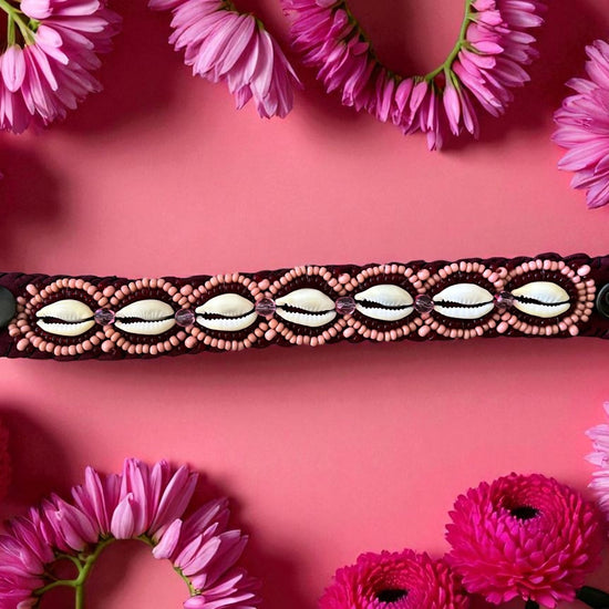 Cowrie bracelet with decorative pattern on a pink background with pink flowers